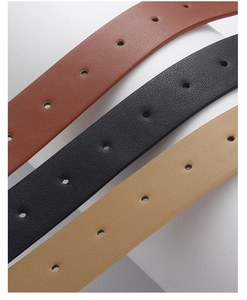 Detail of slim PU leather belts in brown, black, and khaki with lychee grain texture