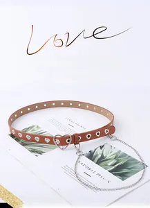 Détail de la ceinture punk en cuir marron avec œillets en cœur et chaîne en métal argenté