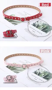 Detail of red and pink leather belts featuring heart buckles and metal chain accents