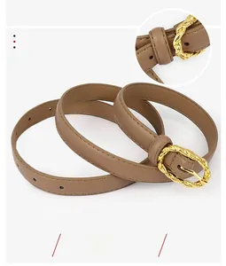 Détail de la boucle tressée dorée sur une ceinture en cuir marron pour robes de femmes