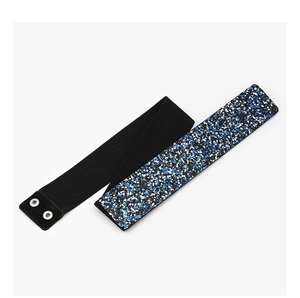 Detalle de cinturón elástico de 5 cm con pedrería azul brillante y botones de metal plateado
