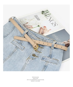 Détail de la boucle dorée vintage gravée sur une ceinture en cuir abricot pour jeans