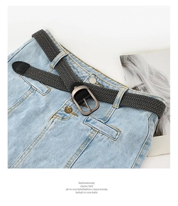 Gros plan sur une ceinture tressée élastique gris foncé avec boucle sur un jean
