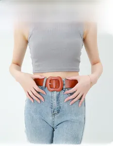 Close-up of a wide brown leather belt with a large square buckle worn on denim jeans