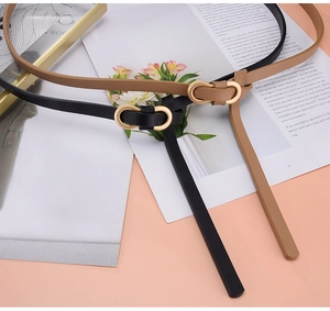 Detail view of stylish black and tan slim leather belts with elegant gold oval buckles