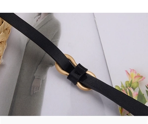 Detail of minimalist black leather skinny belt with elegant gold double-ring metal buckle