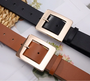 Close-up of black and brown leather belts featuring polished gold square metal buckles