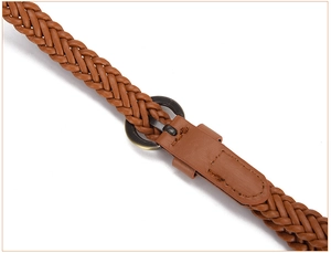 Detail of vintage bronze round buckle and intricate woven texture on a brown belt