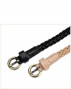 Macro detail of slim woven belts in black and beige with vintage round bronze buckles