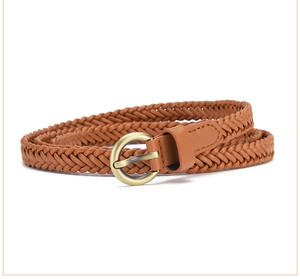 Detail of a thin brown woven belt featuring a vintage golden round buckle on white backdrop