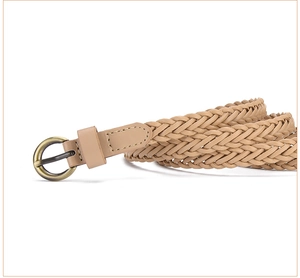 Close-up of khaki woven belt featuring a vintage bronze round metal buckle and braided texture