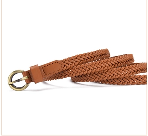 Detail of a brown braided belt with a vintage gold round buckle on a white background