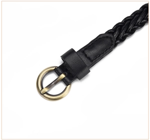 Close-up of vintage bronze buckle and black braided leather strap detail on waist belt