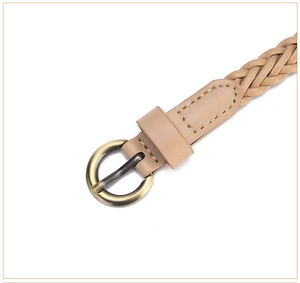 Macro shot of thin woven belt with vintage bronze buckle and detailed light camel texture