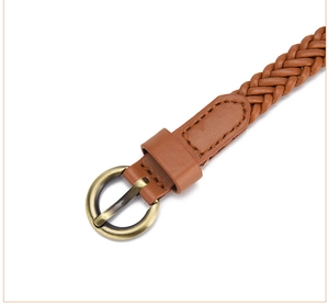 Detail of a brown woven leather belt with a vintage bronze round buckle on white background