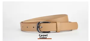 Détail d'une ceinture fine en cuir mat camel avec boucle en métal foncé et trous