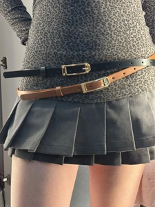 Detail of slim black and brown belts with gold buckles on leopard print outfit