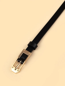 Close-up of black thin belt featuring a gold rectangular buckle with four rivets detail