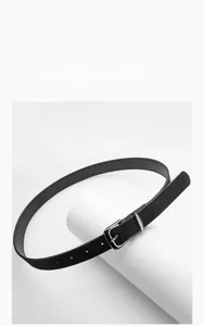 Detail view of a slim black faux suede belt with a matte silver needle buckle on a stand