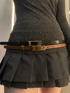 Close-up of black and brown thin leather belts with gold buckles on a model