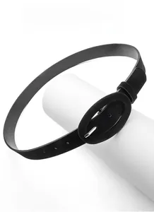 Gros plan d'une ceinture noire en similicuir avec boucle ovale sur un support minimaliste