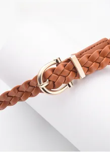 Close-up of brown woven leather belt with a golden horseshoe buckle on a white stand