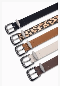 Detail of five assorted narrow belts with metal buckles in leopard, black, tan, and white