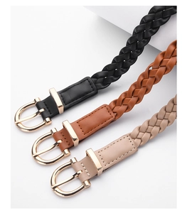 Close-up of woven leather belts in black, brown and apricot with gold metal buckles