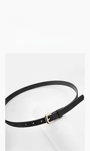 Détail d'une fine ceinture en cuir PU noir avec boucle dorée polie sur support