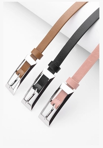 Detailed close-up of three slim leather belts in brown, black, and pink with silver buckles