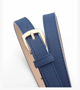 Détail de la ceinture en daim bleu avec boucle dorée et coutures de haute qualité