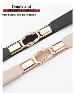 Dettaglio delle cinture nere e beige con fibbie dorate a infinito su sfondo bianco