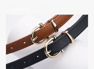 Close-up of thin leather belts with gold U-shaped buckles and lychee texture