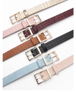 Détail de sept fines ceintures colorées avec texture crocodile et boucles dorées