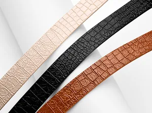 Detail view of smooth crocodile embossed texture on beige, black, and brown belts