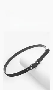 Detail of a matte black suede belt showing the silver round metal buckle and adjustment holes