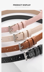 Detail of slim women's faux leather belts featuring crocodile texture and metal buckle