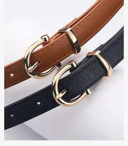 Detail of slim black and brown belts featuring gold U-shaped metal buckles and textured leather