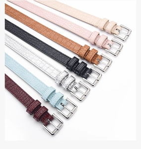 Detail view of thin faux crocodile skin belts in seven colors with silver metal buckles