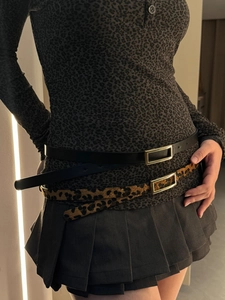 Detail of slim black leather belt and leopard print belt with gold rectangular buckle