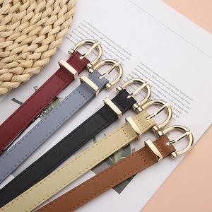 Five assorted colors of women's slim leather belts with gold horseshoe buckles on desk