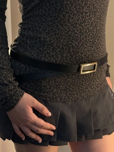 Close-up of stylish black leather belt with polished gold rectangular buckle on jeans