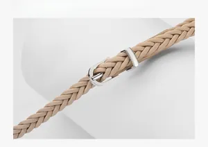 Gros plan détaillé d'une ceinture tressée beige avec une boucle en métal argenté poli en forme D