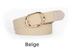 Détail de la ceinture tressée élastique beige avec une boucle ronde en métal doré moderne