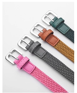 Detail of woven elastic kids belts in pink, grey, brown, and green with metal buckles