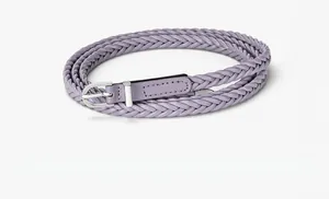Détail d'une fine ceinture tressée en cuir PU violette avec une boucle ardillon argentée