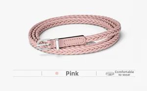 Détail d'une ceinture tressée rose avec une boucle en fer à cheval argentée