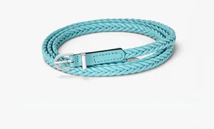 Détail macro d'une ceinture tressée bleu ciel avec boucle à ardillon argentée polie