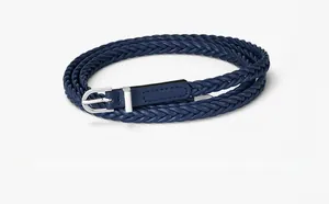 Détail d'une ceinture tressée bleu marine avec boucle argentée et embout en cuir