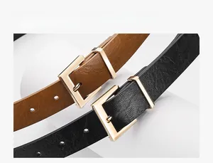Close-up of black and brown leather belts with gold square buckles on a white pedestal